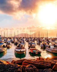 Boats moored in harbor at sunset