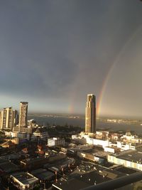 High angle view of rainbow over buildings in city against sky