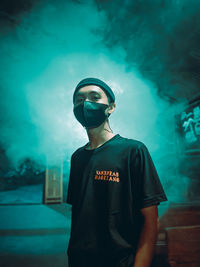 Portrait of young man standing against illuminated light