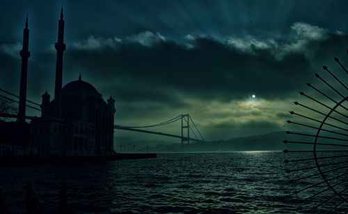 Low angle view of bridge over sea against sky at sunset