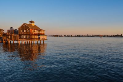 House on pier at lake against sky during sunset