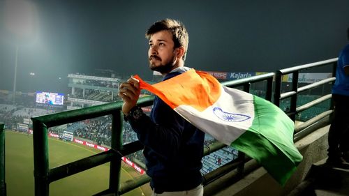 Man holding indian flag while standing at stadium