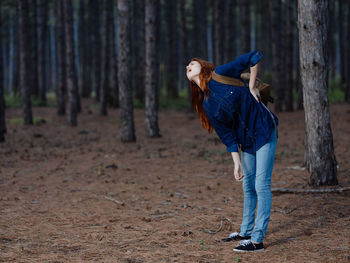 Woman standing by tree trunk in forest