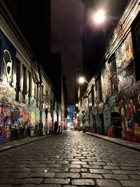 Street amidst illuminated buildings in city at night