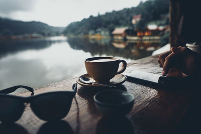 Coffee cup on table by lake