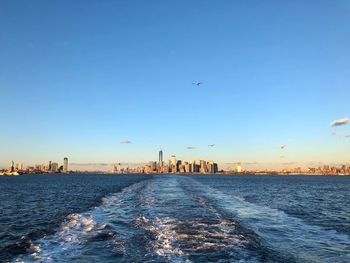 Birds flying over sea against clear sky