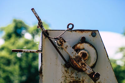 Close-up of rusty machine part against blue sky