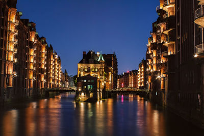 Canal amidst buildings against sky at night