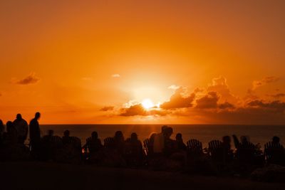 Silhouette people at beach against sky during sunset