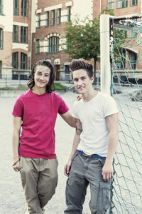 Portrait of confident male high school friends standing by soccer net on schoolyard