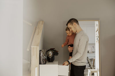 Father carrying toddler daughter in kitchen