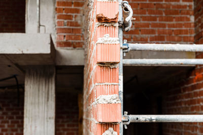 Close-up of old metal structure against brick wall