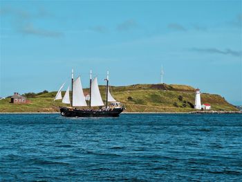 Sailboat sailing on sea against blue sky