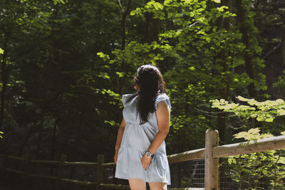 Rear view of woman standing against trees