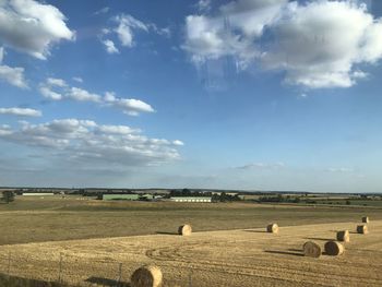 Hay bales on field against sky