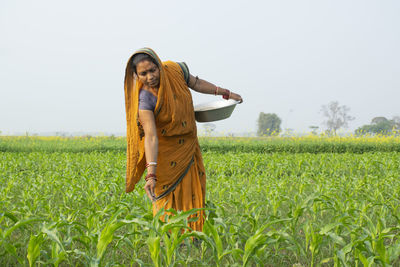 Full length of young woman standing in farm