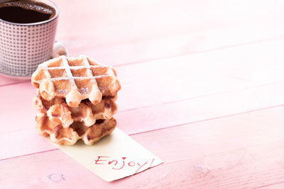 High angle view of coffee cup and waffle on wooden table