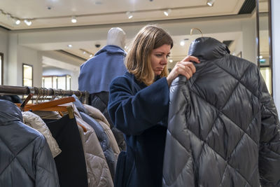 Woman checking padded jacket in clothing store