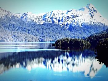 Scenic view of lake by snowcapped mountains against sky