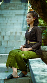 Full length of smiling woman sitting outdoors