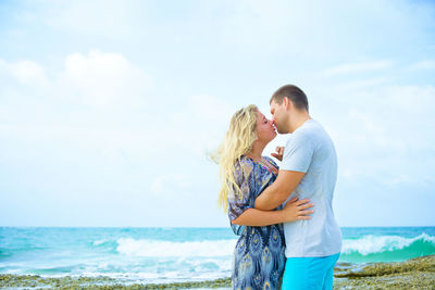 Young couple standing on shore against sea