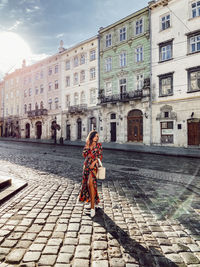 Woman on street against building in city