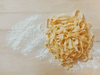 High angle view of pasta and flour on wooden table