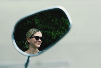 Smiling woman reflecting in side-view mirror