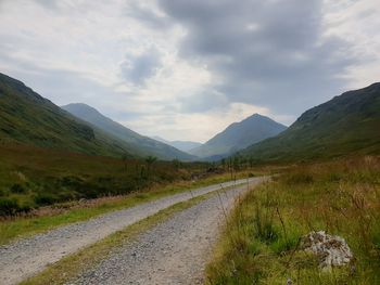 Road leading towards mountains against sky