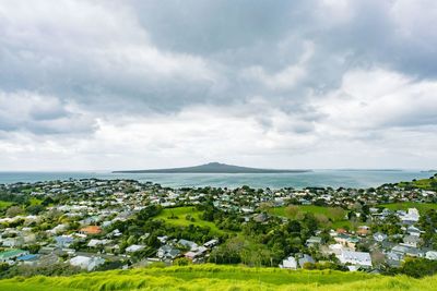 Aerial view of townscape by sea against sky