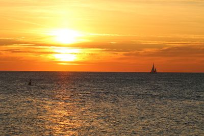 Sailboat sailing on sea against sky during sunset