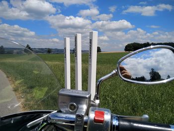 Cars on field by road against sky