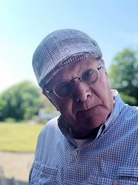 Close-up portrait of man wearing hat against sky