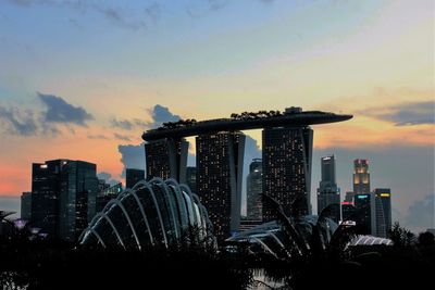 Modern buildings in city against sky during sunset