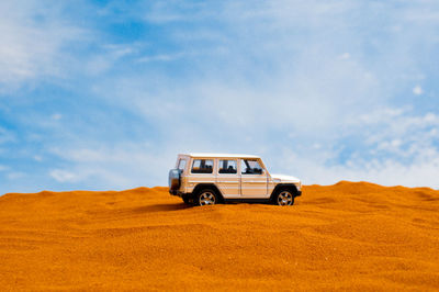 Car on desert land against sky