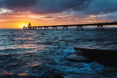 Low angle view of clevedon pier against cloudy sky during sunset