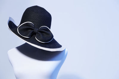 Close-up of black hat on mannequin against white wall
