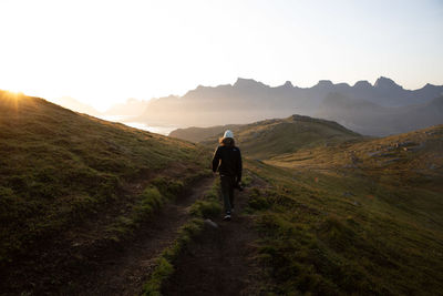 Rear view of man walking on mountain against sky