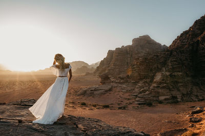 Woman in dress standing on landscape against sky