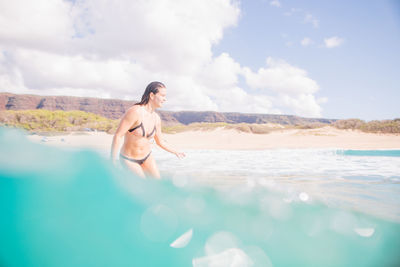 Woman standing in water at coast against sky