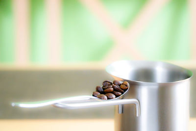 Close-up of roasted coffee beans in spoon on container