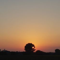 Silhouette trees on field against romantic sky at sunset