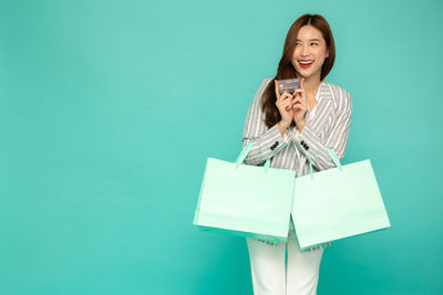 Portrait of smiling woman standing against blue background