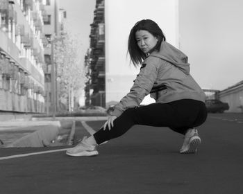 Full length of young woman exercising on road