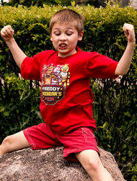 Boy with arms raised in park