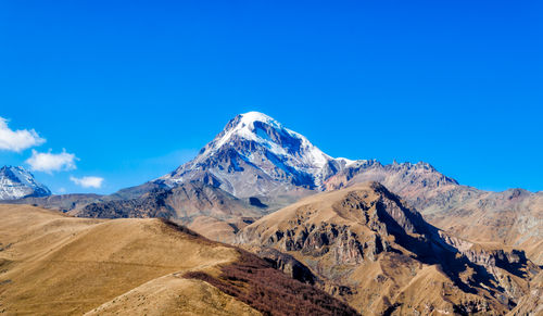 Scenic view of snowcapped mountains against blue sky