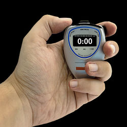 Close-up of hand holding clock against black background