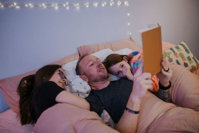 Father reading and snuggling kids in bed