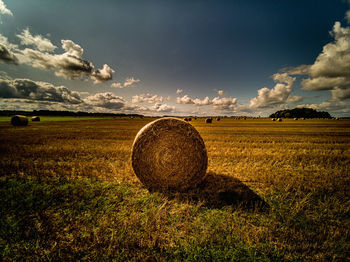 Hay bales on field against sky