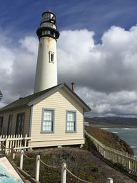 Lighthouse by sea against sky